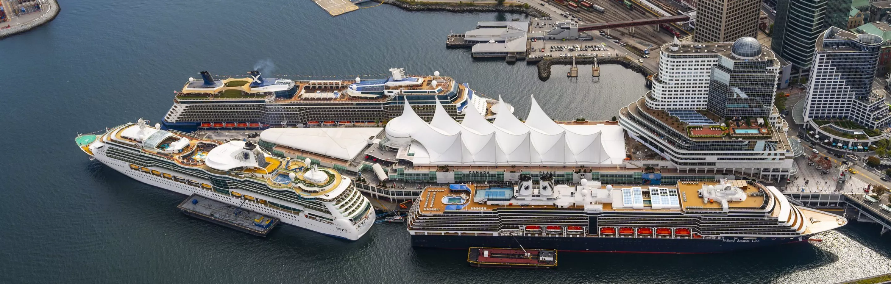 Three cruise ships are berthed around the Canada Place cruise terminal, seen from above