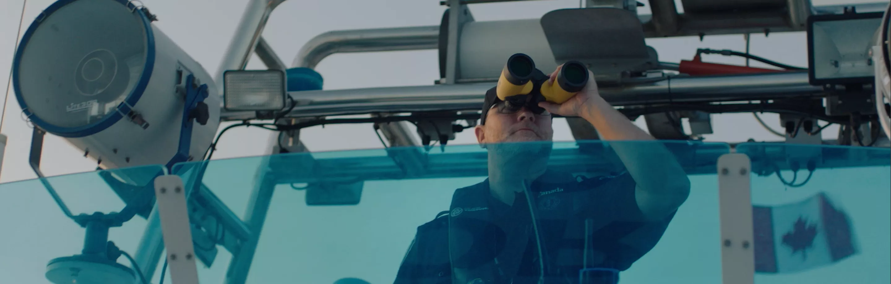 Harbour patrol officer on a boat with binoculars