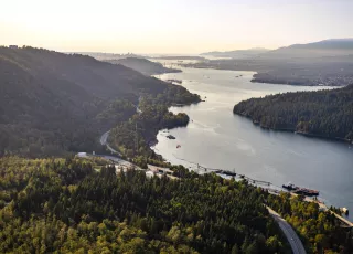 Aerial view of the Fraser River, pictured on the right, running through green forest.